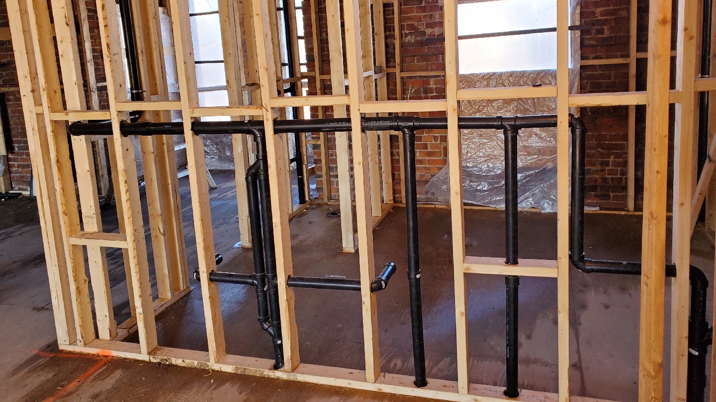 Plumbing rough-in pipework installed behind a wall during a renovation